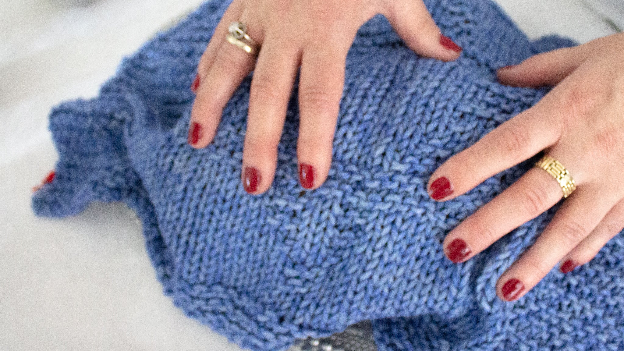 Woman with red pained nails with her hands placed on the blue Magen David challah cover, covering challah.
